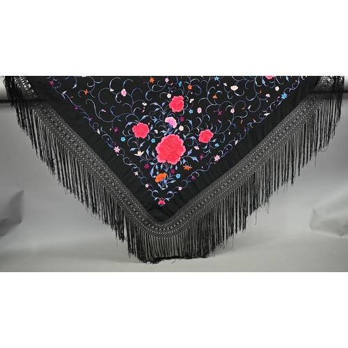 1125 - A circa 1930s Chinese silk 'piano' shawl, the black ground profusely decorated with flowers in colou... 