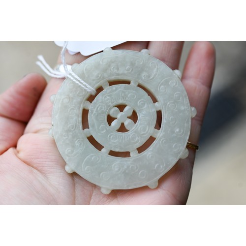 518 - A Chinese pale celadon jade dharmachakra (wheel of dharma) Buddhist amulet or pendant, with central ... 