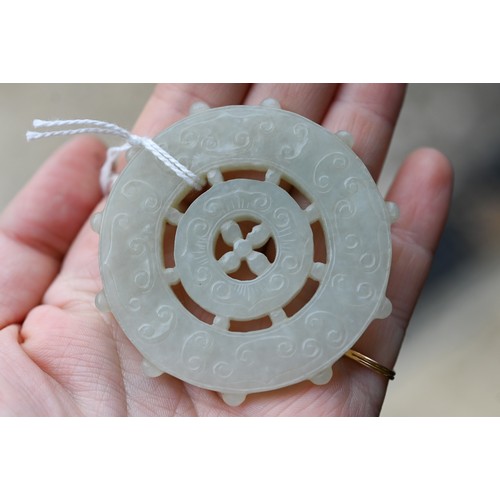 518 - A Chinese pale celadon jade dharmachakra (wheel of dharma) Buddhist amulet or pendant, with central ... 