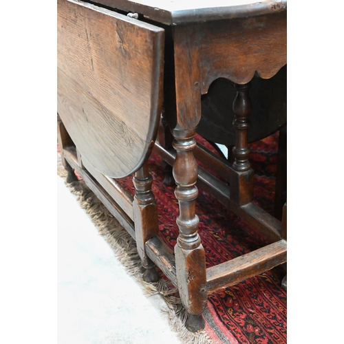 423 - An antique oak drop leaf dining table with end drawer, turned gate-leg action base