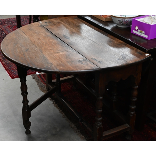 423 - An antique oak drop leaf dining table with end drawer, turned gate-leg action base