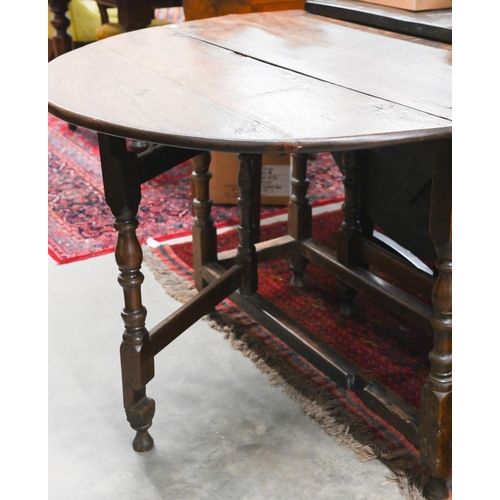 423 - An antique oak drop leaf dining table with end drawer, turned gate-leg action base