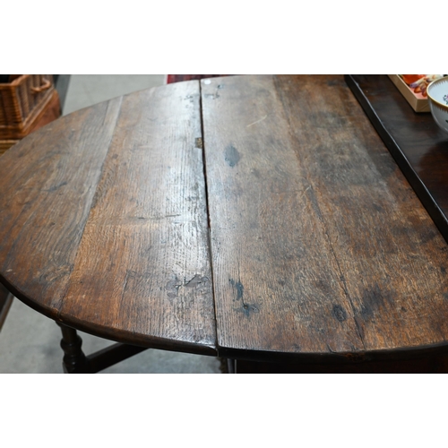 423 - An antique oak drop leaf dining table with end drawer, turned gate-leg action base