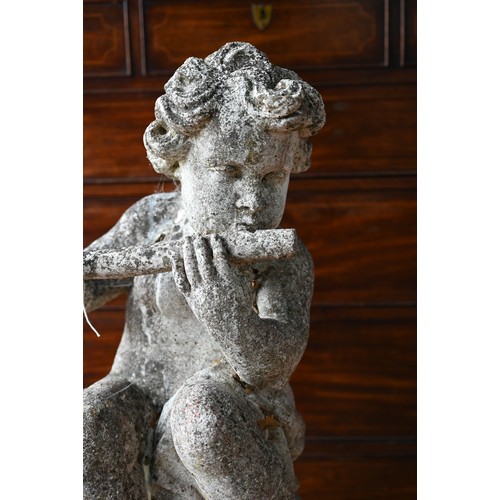 51A - A weathered cast stone cherub playing a flute, seated on a ball, 100 cm h