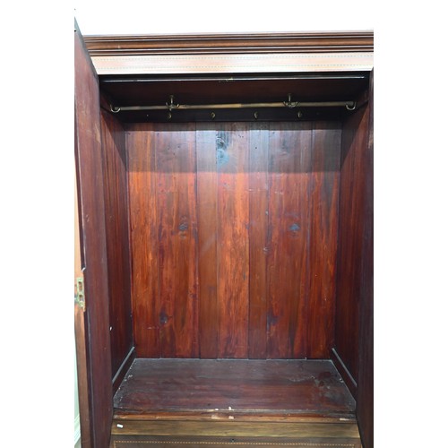 487 - # An Edwardian walnut inlaid wardrobe, the two doors inset with bevelled oval mirrors enclosing hang... 