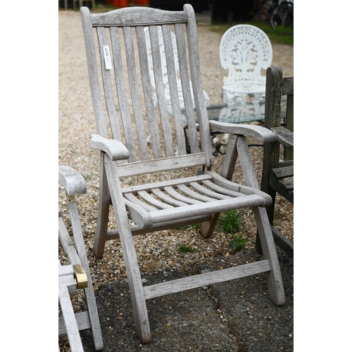 10 - A weathered teak steamer chair with foot extension, to/w a reclining teak armchair and a pair of wea... 