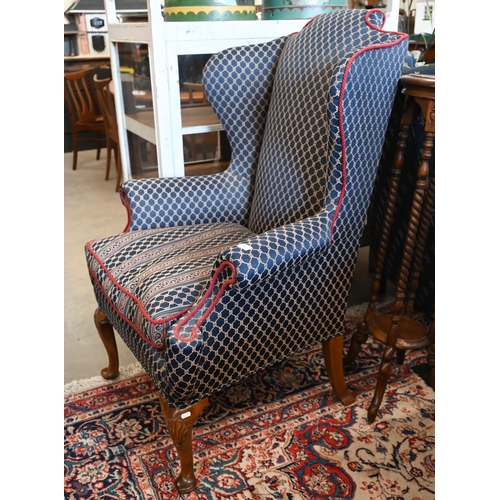 359 - A Georgian style walnut framed wingback armchair with navy blue trellis pattern fabric and shell car... 