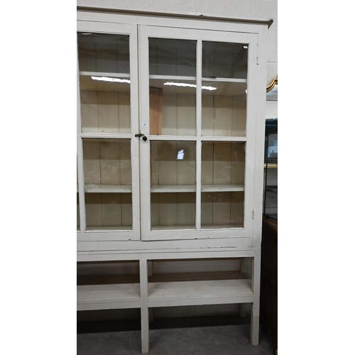 367 - A large cream painted pine bookcase with glazed doors enclosing three shelves with open shelf below,... 