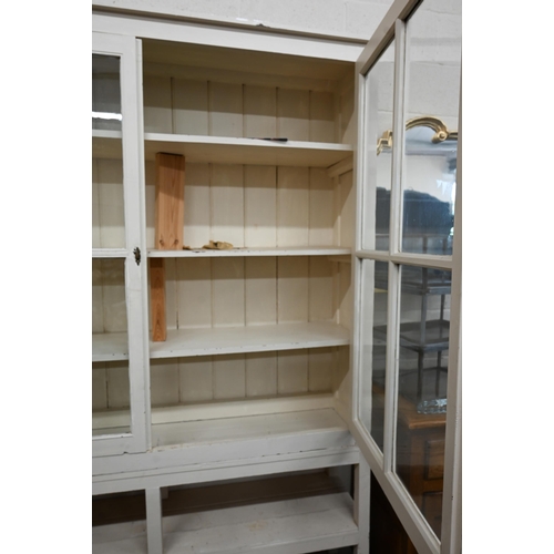 367 - A large cream painted pine bookcase with glazed doors enclosing three shelves with open shelf below,... 