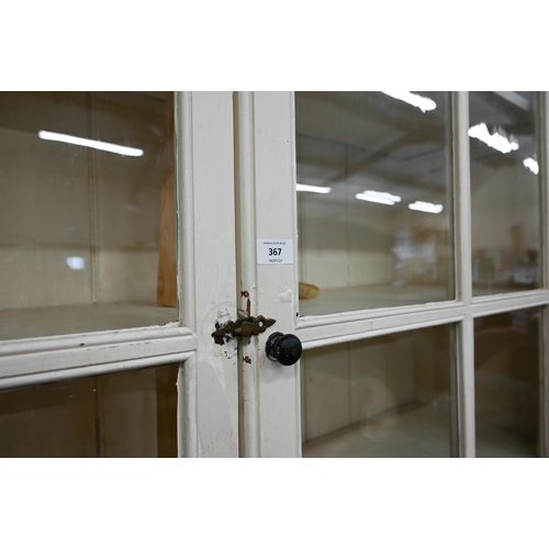 367 - A large cream painted pine bookcase with glazed doors enclosing three shelves with open shelf below,... 