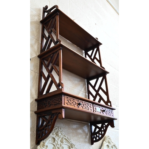 453 - A hardwood three-tier wall shelf with open trellis side panels and two drawers, in the Chinese Chipp... 