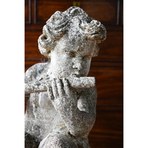 51A - A weathered cast stone cherub playing a flute, seated on a ball, 100 cm h