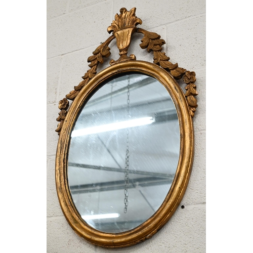 625 - An old oval giltwood framed mirror with urn pediment