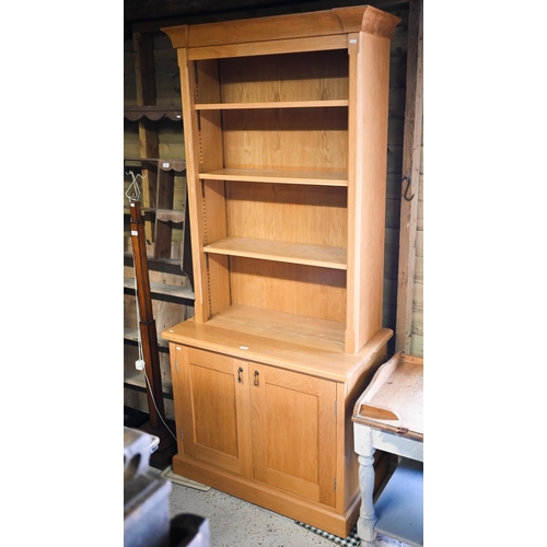 516 - A modern oak cabinet bookcase with three adjustable shelves over base with panelled cupboard, 95 x 5... 