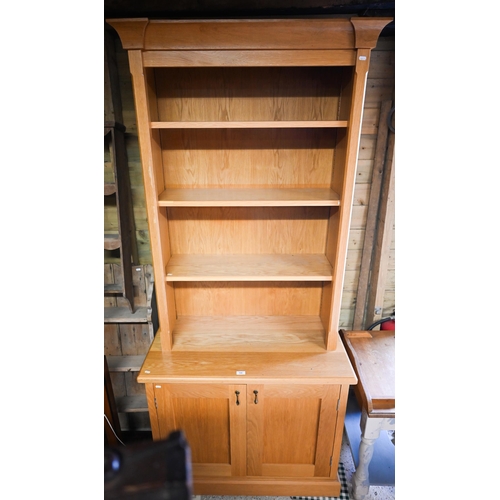 516 - A modern oak cabinet bookcase with three adjustable shelves over base with panelled cupboard, 95 x 5... 