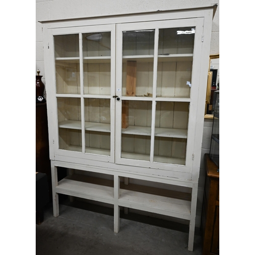 313 - A large cream painted pine bookcase with glazed doors enclosing three shelves with open shelf below,... 