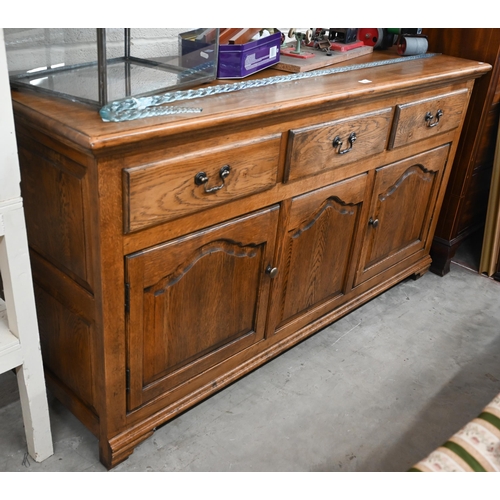 314 - A good quality modern oak sideboard with three drawers over panelled cupboards standing on bracket f... 