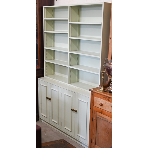 322 - A green-painted bookcase with adjustable open shelving over panelled cupboards, 122 cm wide x 40 cm ... 