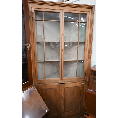 336 - An antique pine floor standing corner cabinet in two sections, glazed top over panelled doors, 108 c... 