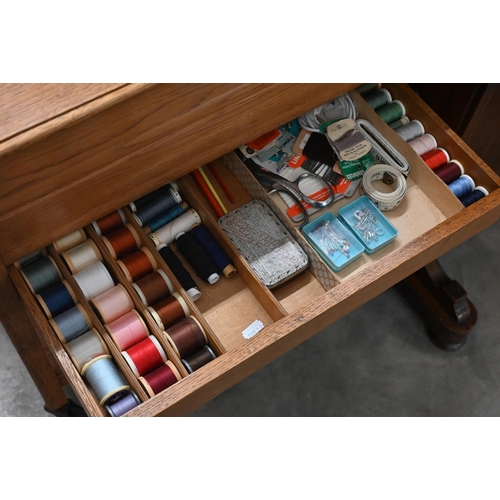 343 - Oak sewing table c/w 'Simplicity' patterns, box of buttons, threads, etc