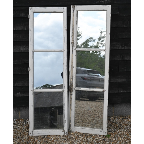 A pair of vintage reclaimed French chateau three pane hardwood windows, in remnants of original painted finish and iron espanolette locking bar and hinges, fitted with mirrors, overall 102 cm w x 164 cm h (as a pair)
