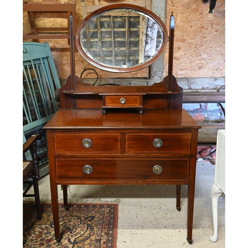 499 - An Edwardian inlaid satinwood oval mirror backed three drawer dressing chest, raised on square legs ... 