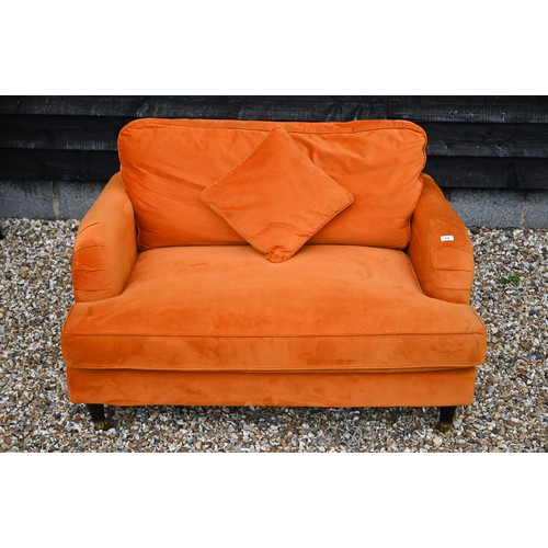 157 - A contemporary plush burnt orange upholstered 'love chair', raised on turned front legs to brass cas... 