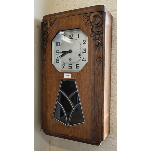 129 - A German Art Deco oak wall clock with octagonal silvered dial, striking and chiming on gongs, 64 cm