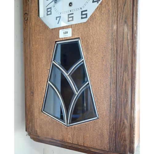 129 - A German Art Deco oak wall clock with octagonal silvered dial, striking and chiming on gongs, 64 cm