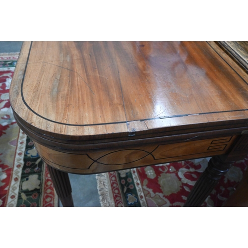 219 - A 19th century mahogany and ebony strung card table with folding baize lined top on turned and reede... 