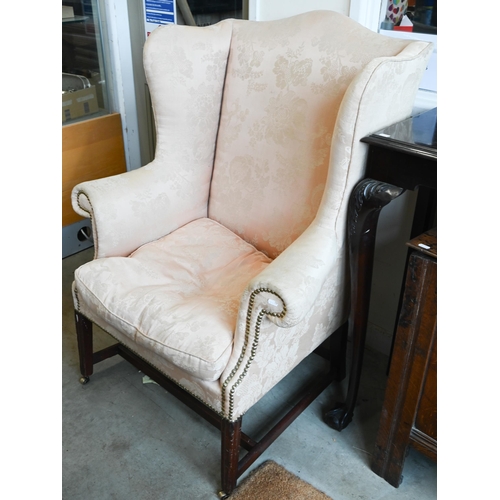 222 - A mahogany framed wingback armchair in peach damask fabric