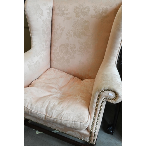 222 - A mahogany framed wingback armchair in peach damask fabric