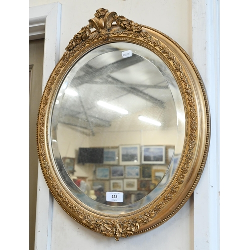 223 - A pair of bevelled oval wall mirrors in foliate gilt frames, 44 cm wide x 54 cm high