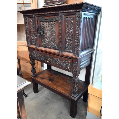 An antique Flemish carved oak cabinet with panelled cupboard, single drawer and open undertier, 106 cm wide x 50 cm deep x 143 cm high