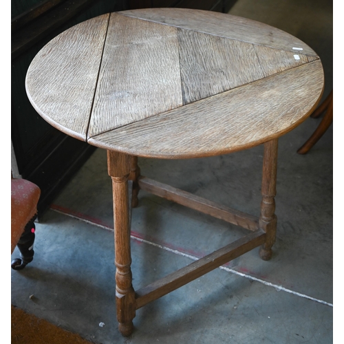 A circular bleached oak drop-leaf table on turned supports united by stretchers, 68 cm diam x 68 cm high