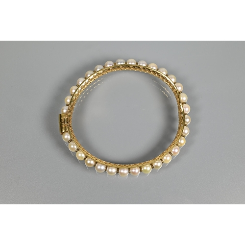 304 - A yellow metal pearl-set bangle, the pierced open grill core set with thirty-one cultured pearls wit... 