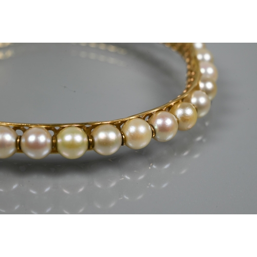 304 - A yellow metal pearl-set bangle, the pierced open grill core set with thirty-one cultured pearls wit... 