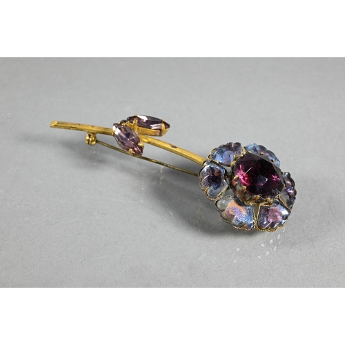 306 - A vintage paste-set brooch in the form of a flower with long stem and leaf decoration, the coloured ... 