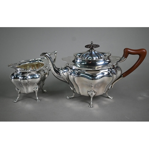 105 - A heavy quality silver teapot and matching milk jug of bombé form, on paw feet, the pot with wood fi... 