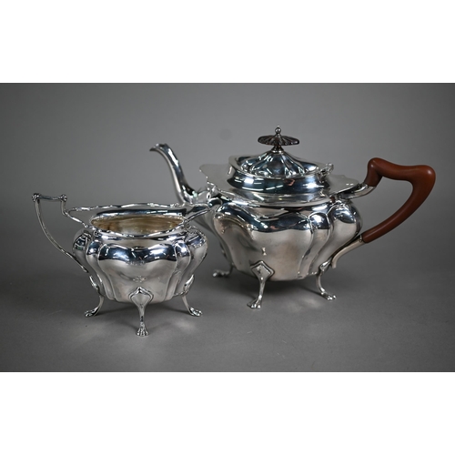 105 - A heavy quality silver teapot and matching milk jug of bombé form, on paw feet, the pot with wood fi... 