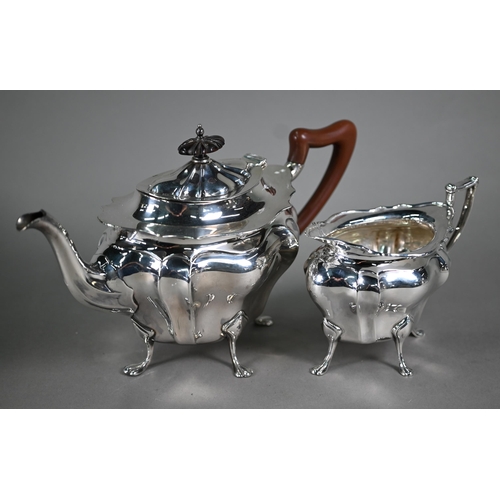 105 - A heavy quality silver teapot and matching milk jug of bombé form, on paw feet, the pot with wood fi... 