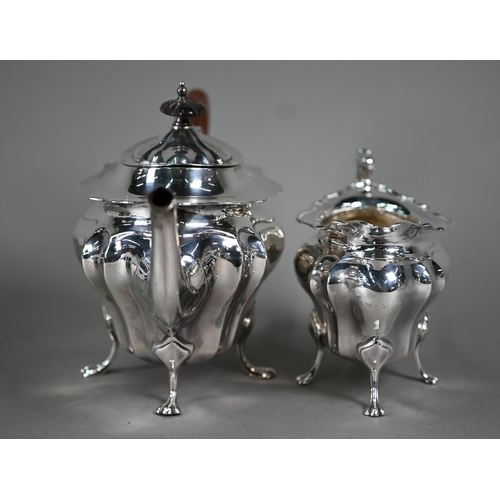 105 - A heavy quality silver teapot and matching milk jug of bombé form, on paw feet, the pot with wood fi... 