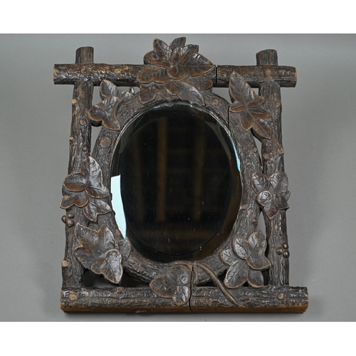 140 - A late 19th century Black Forest wall mirror, the oval bevelled edge mirror set within a frame carve... 