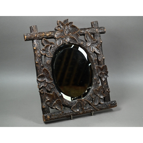 140 - A late 19th century Black Forest wall mirror, the oval bevelled edge mirror set within a frame carve... 