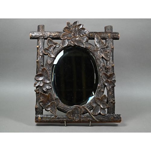 140 - A late 19th century Black Forest wall mirror, the oval bevelled edge mirror set within a frame carve... 