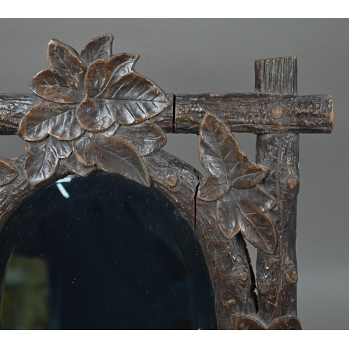 140 - A late 19th century Black Forest wall mirror, the oval bevelled edge mirror set within a frame carve... 