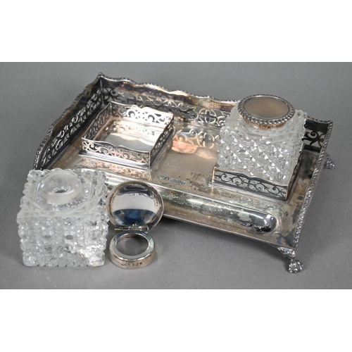 141 - A silver inkstand with pierced gallery and paw feet, fitted with two silver-topped square-cut glass ... 