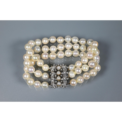 214 - A pearl bracelet, the three-rows of cultured pearls knotted throughout onto fancy white metal set pe... 