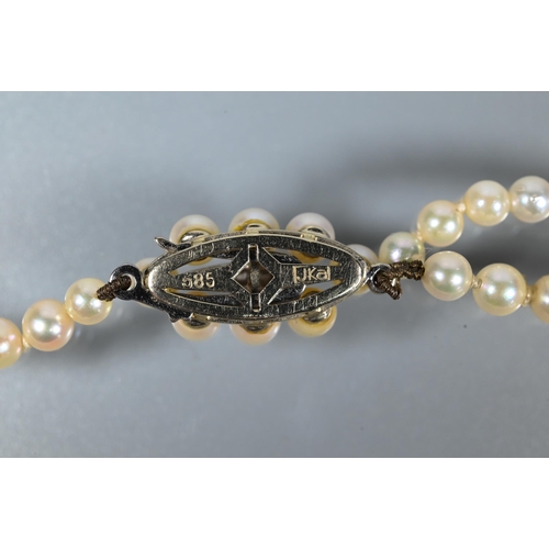 216 - A pearl necklace comprising two rows of graduated cultured pearls on oval pearl and diamond set snap... 