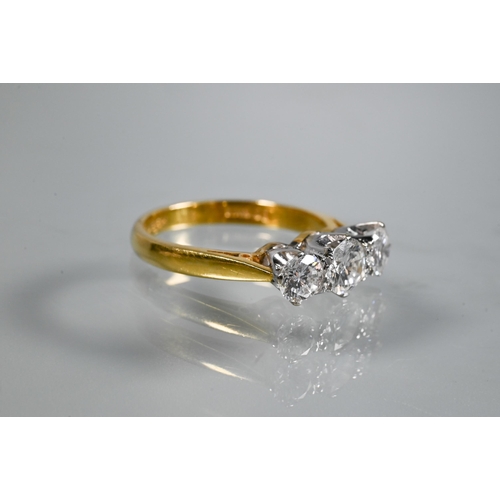 231 - A three-stone diamond ring, the graduated diamonds claw set in platinum, with 18ct yellow gold shank... 